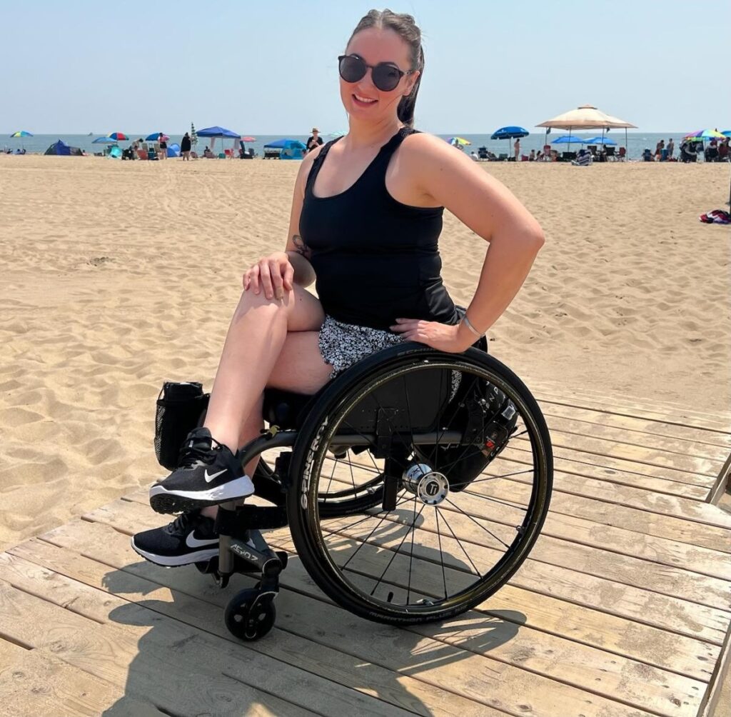 Disabled woman in her wheelchair at the boardwalk on the beach smiling for the camera